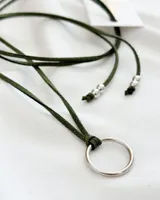 Gargantilla de cuero sintético color verde oliva, con dije circular plateado y cuentas plateadas en los extremos.