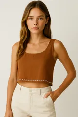 Top corto de viscosa color tostado, con breteles anchos y cuello redondo. Presenta un detalle de bordado geométrico blanco en el ruedo y cierre con botón en la parte posterior.