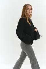 Pantalón de tiro alto con corte acampanado, confeccionado en tejido con patrón de espiga. Presenta cierre frontal oculto y bolsillos traseros insertados.