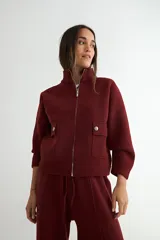 Abrigo de punto negro con cuello alto y cierre frontal completo. Presenta un diseño de corte recto con bolsillos frontales y terminaciones en tejido acanalado.