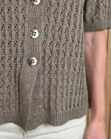 Cardigan de punto color tostado, de manga corta y cuello redondo, con cierre frontal de botones y diseño texturizado.