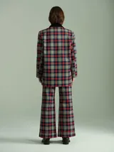 Pantalón de tiro alto con corte ancho y recto, confeccionado en tela de algodón con estampado de cuadros escoceses en tonos azul marino, verde y rojo. Presenta cierre frontal oculto con botones internos y pasacintos en la cintura.