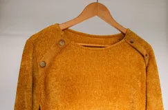 Sweater de chenille color mostaza, de cuello redondo, con mangas largas y apliques de pana acanalada en los hombros decorados con botones.