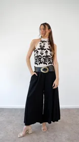 Top de seda color crema con estampado de flores negras, cuello halter y lazo en la espalda.