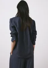 Camisa azul marino con diseño de rayas diplomáticas finas, cuello camisero clásico, mangas largas y cierre frontal con botones.