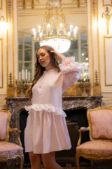 Vestido corto de lino en color rosa claro, con diseño holgado, mangas largas abullonadas con volados en contraste y cierre frontal con botones forrados.