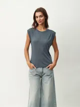 Remera de algodón color gris azulado, con cuello redondo y hombreras marcadas que le dan una estructura definida.