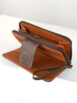 Billetera grande tipo sobre con correa de mano, confeccionada en cuero marrón con detalle central de cuero con pelo vacuno en tonos marrón, negro y blanco. Presenta cierre perimetral y solapa frontal con broche magnético y logo de búho grabado.