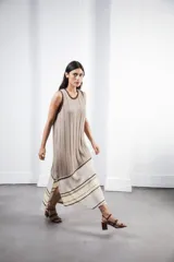 Vestido midi tejido en punto canalé negro con detalles en lurex plateado. Presenta calado artesanal en el ruedo, abertura lateral y etiqueta de cuero en la parte trasera del cuello.