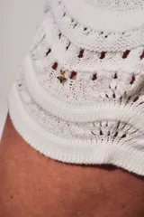 Short tejido de punto con diseño de ondas y calados, color blanco. Presenta cintura elástica acanalada y corte mini.