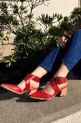 Zapatos de tacón ancho color camel con textura símil serpiente, punta fina y tiras cruzadas con hebilla metálica grande en el lateral.