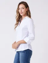 Camisa blanca entallada de algodón con escote en V y cuello con solapa. Presenta un diseño frontal con alforzas horizontales en la pechera y mangas tres cuartos con puños anchos rebatibles.