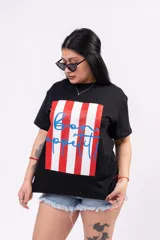 Remera oversize blanca de algodón suave con cuello redondo, con un estampado central que combina franjas verticales rojas y la frase 'bon appétit!' escrita en azul con tipografía cursiva.