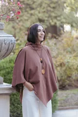 Poncho de textura suave tipo polar, color marrón, con cuello alto y diseño amplio de corte asimétrico.