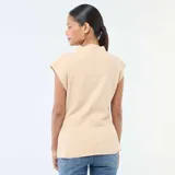 Sweater sin mangas color beige de tejido de punto, con cuello alto y detalle de hebilla metálica en forma de corazón en el lateral de la cintura.
