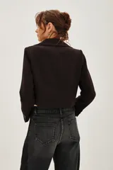 Saco de corte sastre entallado, color negro, con solapas clásicas, cierre frontal de un botón y mangas largas con detalle de botones en los puños.