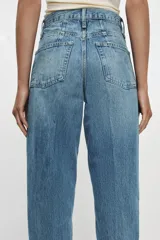Jeans de tiro alto con corte tapered y largo al tobillo. Presenta cinco bolsillos, trabillas en la cintura, cierre frontal con cremallera y botón, y detalle de raya planchada en el delantero.
