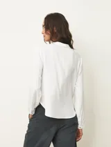 Blusa de manga larga color blanco, con cuello mao y abertura frontal tipo gota con cierre de botón. Presenta un diseño fluido con frunces en el escote y puños abotonados.