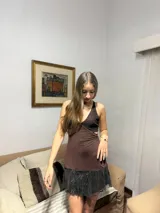 Vestido corto plateado con lentejuelas, escote en V y cut-outs laterales bajo el busto. Breteles finos que se cruzan en la espalda y atan atrás. Volado en el ruedo.