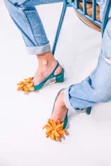 Zapato de tacón turquesa con diseño en escamas y flor naranja en la punta. Tacón de 6,5 cm, plantilla celeste, interior de piel y suela de cuero. Fabricado en España.