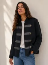Campera negra estilo húsar con apliques de símil cuero horizontal en el frente, cuello mao y detalles de botones metálicos grabados.