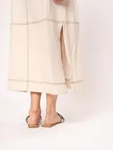 Vestido largo color crudo de lino, con silueta recta, escote en V, breteles anchos, detalle de elástico en la espalda y tajos laterales.