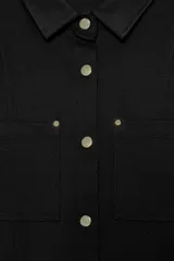 Camisa entallada color marrón oscuro, con cuello camisero y manga larga. Presenta dos bolsillos de plastrón en el delantero y cierre frontal con botones a presión dorados.