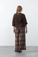 Cardigan de tejido de punto color marrón chocolate, con diseño de trenzas en el frente y mangas. Presenta cuello redondo, cierre frontal con botones al tono y puños acanalados.