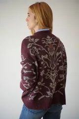 Buzo de tejido de punto en color marrón con un patrón ornamental floral en color celeste. Presenta cuello redondo, mangas largas y un corte holgado.