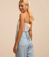 Enterito largo de jeans celeste, con breteles finos, escote recto, bolsillos delanteros y traseros, y trabillas en la cintura.