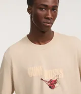 Remera de algodón color beige con cuello redondo y mangas cortas, de corte comfort. Presenta un gran estampado en la espalda de un águila con flores y la inscripción de la banda Guns N' Roses.