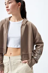 Canguro cropped con cierre frontal y tirador metálico. De mangas largas con estampa abstracta en contraste.