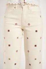 Pantalón de jean color crudo, de corte recto y tiro medio, con bordados de flores marrones.