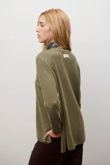 Sweater de tejido de punto color beige, con escote en V y mangas largas. Presenta un diseño básico y versátil de corte recto.