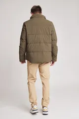 Cazadora acolchada tipo puffer color verde militar, con capucha desmontable, cierre frontal y bolsillos laterales con cierre.
