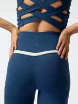 Calza deportiva azul con cintura cruzada en forma de V y detalle bicolor en tono beige debajo de la pretina.