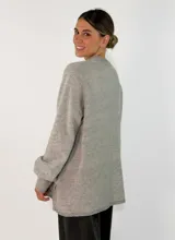 Sweater de tejido de punto en color azul marino, con cuello redondo, mangas largas con puños acanalados y ajuste holgado. Presenta un pequeño aplique decorativo en el ruedo.