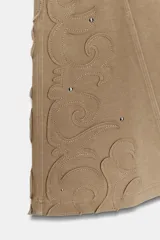 Pantalón de corte flare confeccionado en mezcla de algodón con efecto lavado. Presenta tiro medio, cintura elástica y detalles de tachas y aplicaciones bordadas en el bajo de las piernas.