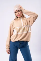 Buzo oversize de algodón color beige, con cuello polo y cierre frontal parcial. Presenta una franja horizontal blanca en el pecho con el texto 'SOHO' estampado en color beige.