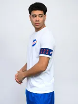 Remera de fútbol blanca con manga derecha azul marino y manga izquierda blanca con una banda azul marino y detalles rojos. Tiene el escudo del Club Nacional de Football en el pecho.