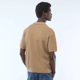 Remera de punto gofrado color kaki con cuello polo, cierre frontal con botones y mangas cortas.