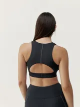 Top deportivo negro de alta sujeción con tejido Shape_Tech, cinta reflectante en el delantero, costura reflectante en la espalda, abertura posterior para mayor transpirabilidad y cierre ajustable en la espalda.