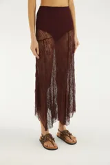 Falda larga bordó de encaje translúcido, de tiro alto y diseño asimétrico con bajo puntiagudo. Incluye hot pants interiores.