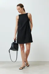Vestido corto negro de lino, corte recto, sin mangas y con bolsillos laterales.