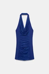 Vestido mini de cuello halter con escote drapeado, confeccionado con combinación de tejidos y detalle de frunces en el frente. Cuenta con forro interior y cierre lateral con cremallera oculta.