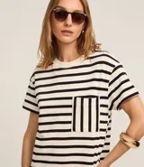 Vestido corto estilo camiseta de algodón, con cuello redondo, mangas cortas y bolsillo en el pecho. Presenta un patrón de rayas horizontales blancas y negras.