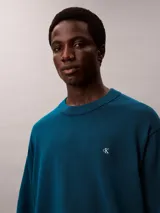 Sweater Calvin Klein de corte relajado, color azul oscuro, con cuello redondo y el logotipo CK bordado en contraste en el pecho. Presenta puños, cuello y dobladillo acanalados.