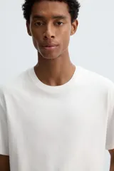 Camiseta de algodón de peso medio, color gris oscuro con efecto lavado ligero. Presenta cuello redondo y manga corta.