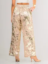 Conjunto de dos piezas compuesto por camisa de manga larga con cuello camisero y pantalón de corte recto y holgado. Ambas prendas presentan un acabado metalizado con efecto desgastado en tonos dorados.