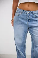 Jean de tiro medio en color celeste, con corte recto y holgado. Presenta detalle de tachas metálicas pequeñas a lo largo de las costuras laterales y en la zona de los bolsillos delanteros.